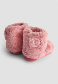 Roze faux fur pantoffels met een korte enkelhoogte, zachte textuur en een ronde neus. Voorzien van een rubberen zool voor grip en comfort.