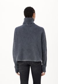 Pull en maille épaisse à col cheminée marine avec un motif à rayures verticales, longueur cropped et texture côtelée. Fini avec des poignets et un ourlet larges.