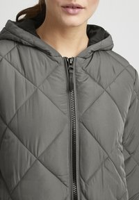 Gequilted grijze hoodie met een ritssluiting aan de voorkant, met een gladde buitenkant en contrasterende zwarte voering. Opvallend ruitenstiksels patroon.
