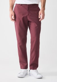 Burgundy pants made of woven fabric, featuring a slim fit design, straight legs, and side pockets. Paired with white sneakers.