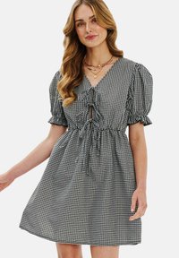 Čierno-biele šaty s károvaným vzorom, puff rukávmi, sťahovacím pásom a V-krkom. Ľahký materiál s voľným strihom a naberanými detailmi.