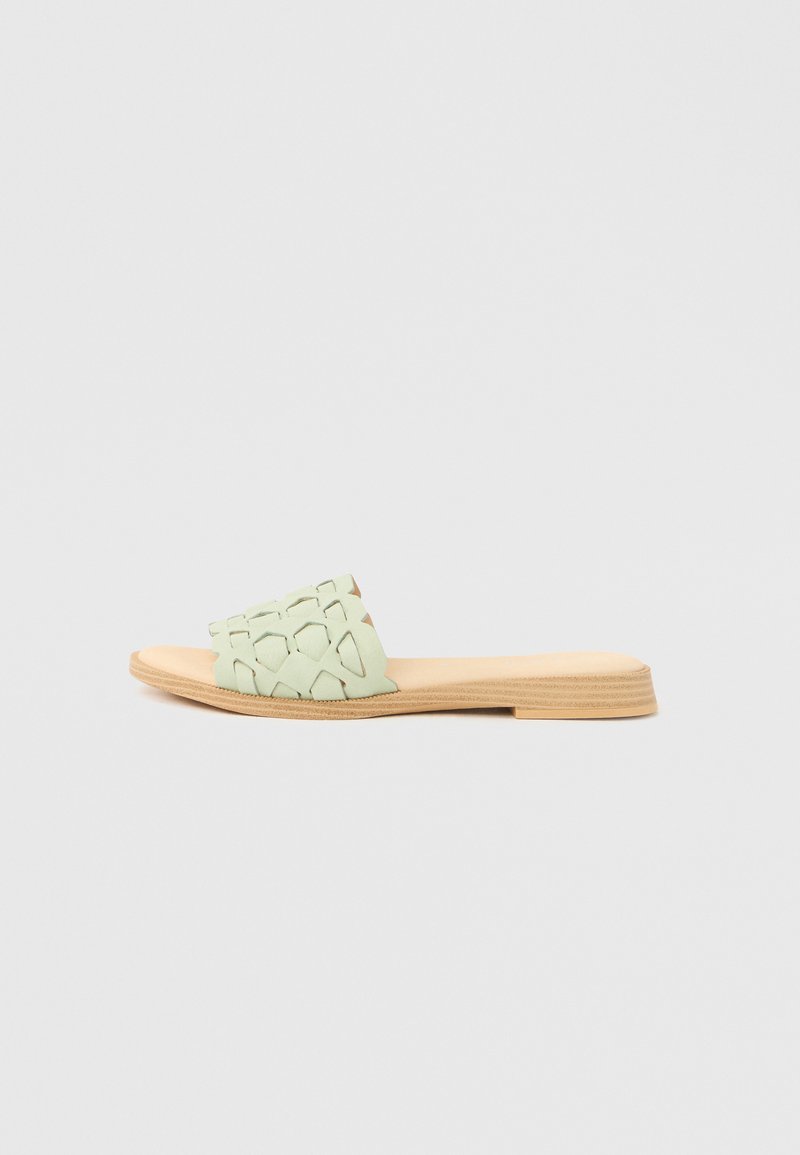 Ανοιχτό πράσινο σανδάλι χωρίς κορδόνια με σχέδιο κοψίματος στο πάνω μέρος και σόλα με υφή φυσικού ξύλου. Επίπεδο και μινιμαλιστικό προφίλ.