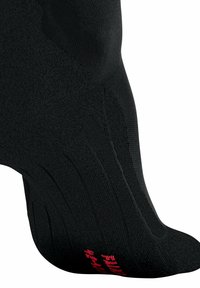 Calza sportiva nera con tessuto testurizzato, punta rinforzata e supporto per l'arco del piede, con branding rosso stampato sul lato.