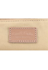 Beige fabric with stitched light brown leather label reading "Gusti Leder Made in Italy" in embossed text.