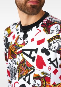 Felpa bianca con un design di carte da gioco in rosso, nero e giallo. Include vari simboli e personaggi delle carte con stampe bold.