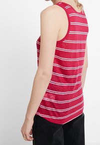 Röd linne med vita horisontella ränder, i bomullsmaterial, design med låg skopad rygg och avslappnad passform. Matchas med mörka jeans.