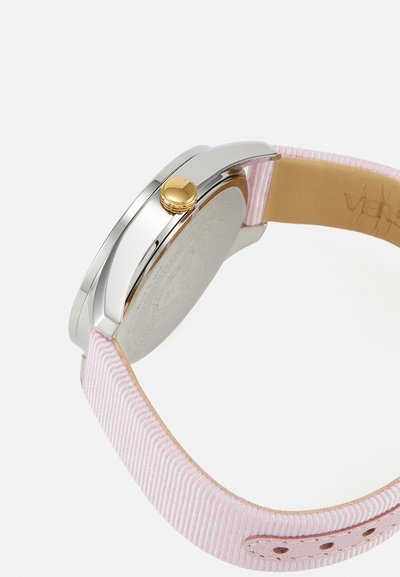 Silver case watch with a gold crown, featuring a light pink fabric strap, textured surface, and a polished back with engraved details.