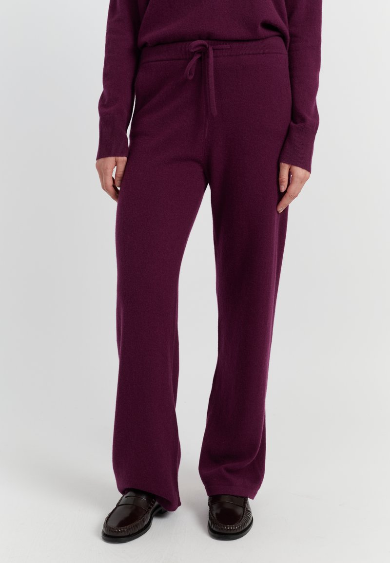 Paarse gebreide loungebroeken met een trekkoord in de taille, recht gesneden ontwerp en een zachte textuur, gecombineerd met donkerbruine loafers.