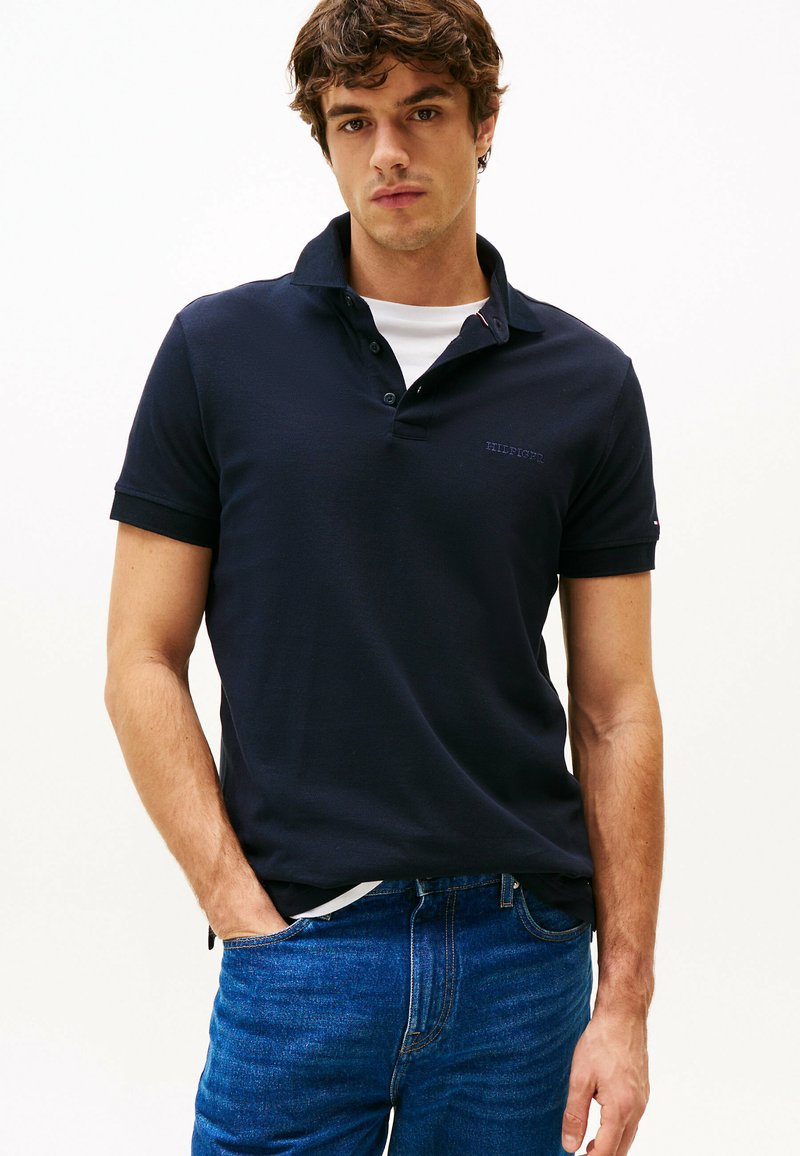 Navy poloshirt van katoen, voorzien van een kraag, een twee-knopen sluiting en een klein logo op de borst, gecombineerd met blauwe jeans.
