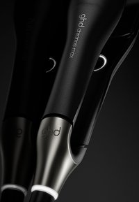 GHD stylingtool in mat zwart, met een metallic zilveren basis en verlichte accenten, voorzien van het "ghd" logo in textuurdetail.
