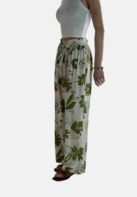 Zijdeliljke broek met bloemenpatroonte in lichtgewicht stof, met groene en perzikkleurige accenten op een lichte achtergrond, met een elastische tailleband.