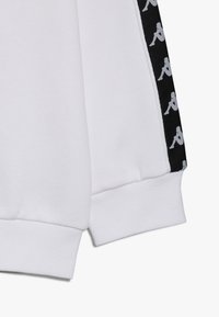 Felpa bianca con tessuto strutturato, polsini elastici e pannello laterale nero con motivo ripetuto di logo grigio.