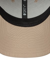 Beige baseball cap with a black brim. Textured fabric and visible stitching details. Label inside states "9FORTY."