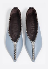 Płaskie buty o spiczastym nosku, wykonane z jasnoniebieskiej skóry z srebrnym suwakiem, posiadające gładką teksturę i miękką brązową wkładkę.