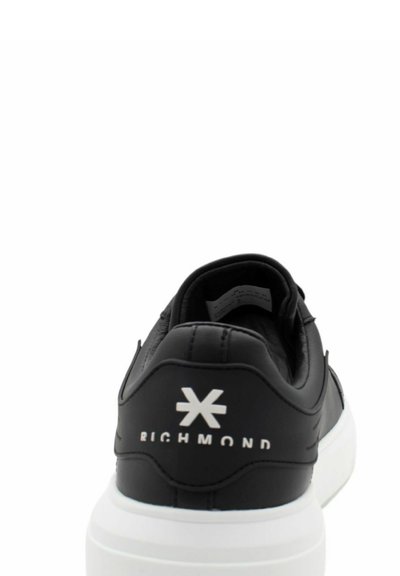 Sneaker in pelle nera con suola in gomma bianca. Presenta un colletto imbottito, logo in rilievo sul tallone e dettagli testurizzati.