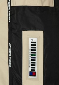 Il tessuto della giacca beige e nera presenta un termometro per il comfort in una tasca rettangolare con scala numerica e indicatori di colore.