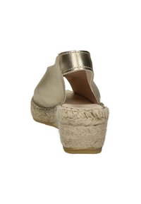 Beige espadrille wedge sandalen met een metallic accent bij de hak, een gevlochten jute platform en een open achterkant.