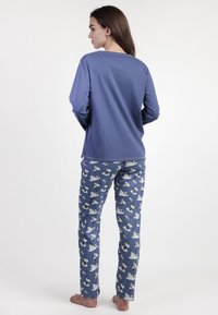 Top de manga larga azul combinado con pantalones azules estampados que presentan osos polares y lunas. Tejido suave, corte relajado y detalles de costura mínimos.