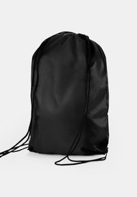 Sort rygsæk med snøre, lavet af nylonstof, stående oprejst med snore, der strækker sig ud fra begge sider, på en ensfarvet hvid baggrund.