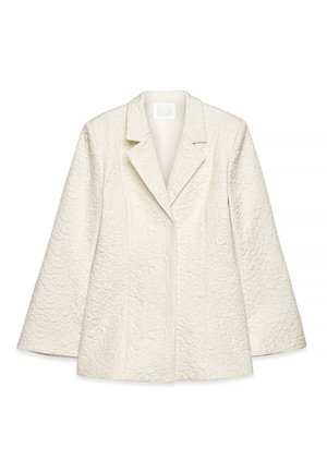 Blazer blanco texturizado con mangas largas, solapas anchas y un ajuste entallado, mostrado sobre un fondo blanco.