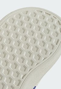 Gumová podešev boty s hexagonálním vzorem, který obsahuje texturované oblasti. Barva je převážně světle béžová s mírně vyvýšeným designem.