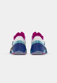 Sportliche Schuhe mit einem weißen Obermaterial, rosa und blauen Akzenten, strukturiertem Absatz und einer mehrfarbigen Sohle mit einem Zickzackmuster.