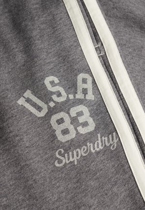 Grijze sweatshirt met een witte gestreepte rits en de opdruk "U.S.A 83" en "Superdry" in een contrasterende lichte kleur. Zachte stoftextuur.