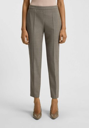Tailored gray trousers with subtle texture, flat front, and tapering legs. Paired with shiny neutral stiletto heels.