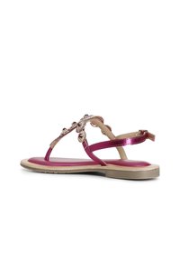Sandali metallici rosa con suola piatta, caratterizzati da decorazioni sui cinturini e una cinghia regolabile alla caviglia per una vestibilità personalizzata.