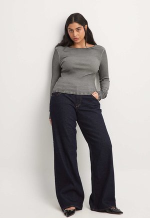 Grijze geribde lange mouw top gecombineerd met een wijdvallende spijkerbroek van donker denim. De top heeft een boot neckline en een getailleerde pasvorm.