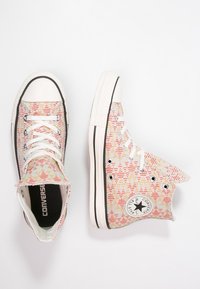 Hoge sneakers met een multicolore geometrisch patroon, witte rubberen neuskap, zwarte zoolrand en het klassieke All Star-logo aan de zijkant.