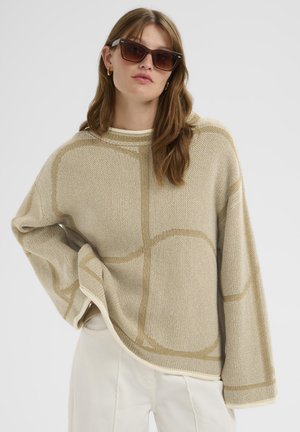 Beige knit sweater with loose fit, featuring a geometric design in a lighter beige, contrasting cream trim, and wide sleeves.
