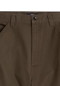 Braune Baumwollhosen mit Knopfverschluss, Gürtelschlaufen und glatter Textur. Sichtbare Vorderasche und Reißverschlussdetails.