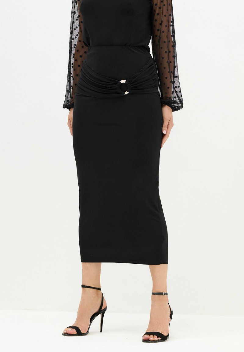 Czarna midi sukienka z przezroczystymi długimi rękawami w kropki, marszczonym detalem w talii oraz okrągłym akcentem z metalowym wykończeniem. Stylizowana z czarnymi sandałami na wysokim obcasie.