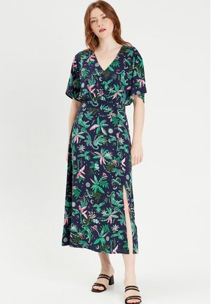 Robe maxi florale avec un fond bleu marine, des feuilles vertes et des accents roses. Décolleté en V profond, manches amples et fente sur le côté. Tissu doux.