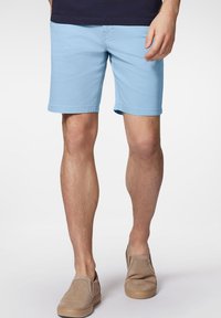 Jasnoniebieskie bawełniane szorty o prostym kroju, z bocznymi kieszeniami i gładką fakturą, w połączeniu z beżowymi butami wsuwanymi.