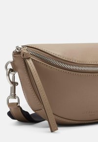 Brązowa skórzana torebka na ramie o zaokrąglonym kształcie, z srebrnym zamkiem błyskawicznym i odpinanym paskiem. Charakteryzuje się fakturowanym wykończeniem i minimalistycznym designem.