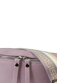 Lila leren tas met ritssluiting en dubbele handvatten. Inclusief een verstelbare schouderband met een patroon en crèmekleurige en gouden accenten.