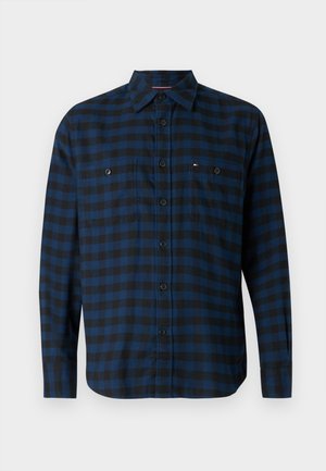 Garais piedurkņu krekls zilā un melnā rūtu rakstā, ar pogām aizdarāmu apkakli, divām krūšu kabatām un smalku logotipa detaļu. Kokvilnas maisījuma audums.