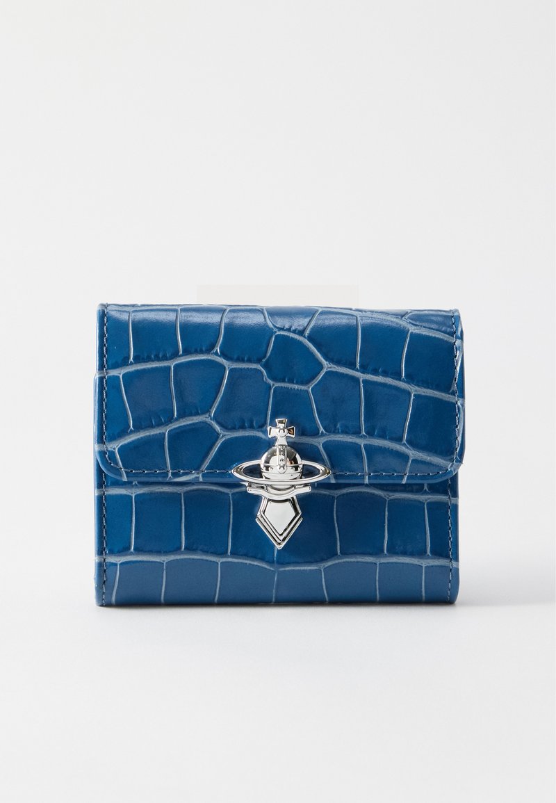 Portefeuille bleu à texture crocodile avec un emblème métallique argenté en forme de planète avec une croix, sur fond blanc.