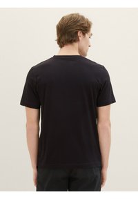 Tricou negru cu mânecă scurtă, cu decolteu rotund, fabricat dintr-un material neted, având un design simplu și o croială relaxată, văzut din spate.