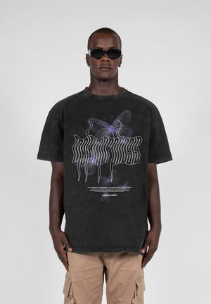 Sort oversized bomulds t-shirt med et sommerfugle-grafik i lilla og hvid, med stiliseret tekst og et afslappet fit. Let slitage synlig.