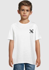 Camiseta de algodón blanca con mangas cortas, cuello redondo, que presenta un pequeño diseño gráfico negro en el área del pecho izquierdo.