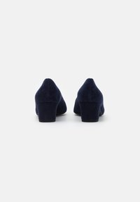 Tacones de terciopelo azul marino con punta redonda y tacón bajo en bloque. Textura suave, diseño sencillo y sin herrajes visibles.