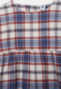 Bavlněné šaty s kostkovaným vzorem v červené, modré a bílé barvě, s áčkovým střihem a nařaseným pasem pro texturu.