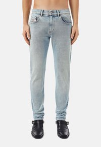 Light blue denim jeans with a slim fit, five-pocket design, and visible fading. Features a button and zipper closure at the waist.