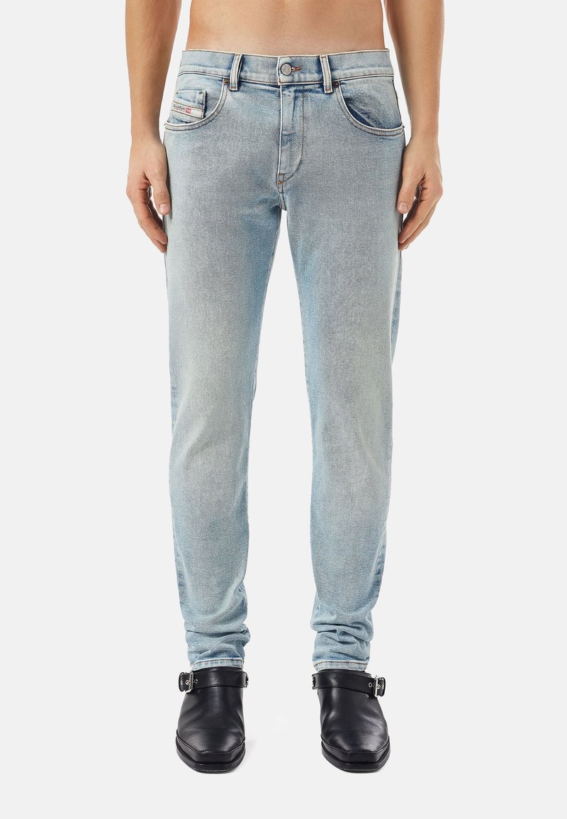 Light blue denim jeans with a slim fit, five-pocket design, and visible fading. Features a button and zipper closure at the waist.