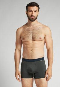 Pánské boxerské trenýrky v tmavě šedé barvě s námořnickým pasem. Vyznačují se těsným střihem a hladkou texturou, s přední kapsou a švy.