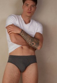 Grijze katoenen slips met een voorvak, voorzien van een naadloos ontwerp en een elastische tailleband, gecombineerd met een witte t-shirt met ronde hals.