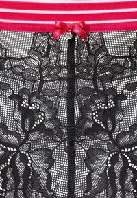 Schwarze Spitzenunterwäsche mit Blumenmustern, mit einem rosa gestreiften Bund und einem kleinen rosa Schleifchen mit einem Strassdetail in der Mitte.